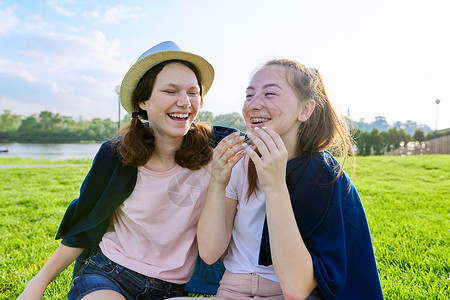 女友几时有在阳光明媚的夏日 坐在草地上玩得开心的少女女友女士微笑情绪友谊青少年女学生闲暇女朋友幸福快乐背景