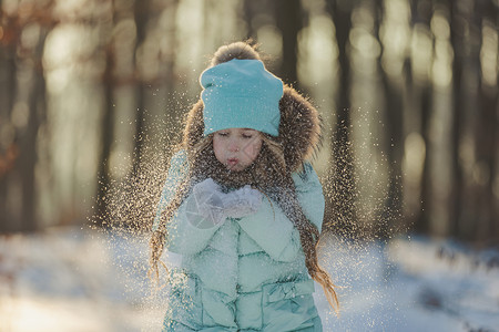 帮她一把女孩吹在雪上 她的手套上的雪耀斑公园一个男孩假期幸福乐趣童年享受背景青少年背景