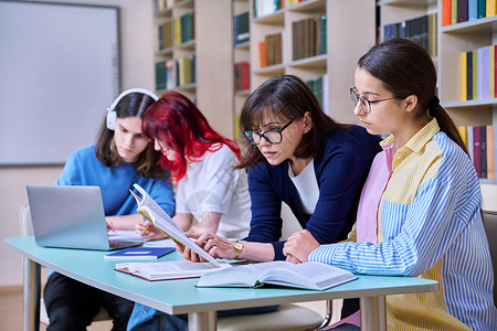 青少年学生群体和在图书馆书桌上的师范学习桌子中学女士多样性教科书学校微笑小学生教育女性背景图片