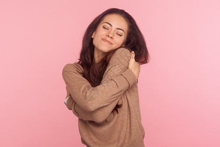 自尊自爱粉红色背景的年轻情感女人的肖像自豪拥抱女士手势自尊身体崇拜女性幸福姿势背景