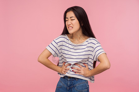 粉红色背景的亚洲年轻女性肖像卫生医疗怀孕药品伤害女孩疾病胀气便秘胃炎图片
