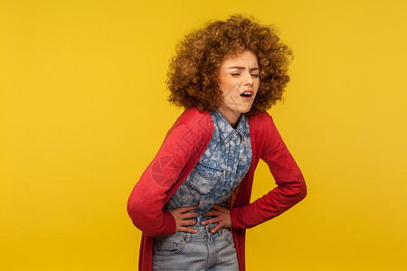黄色背景的情绪卷发女孩的肖像肠胃女性胃炎保健冒号医疗怀孕腹泻问题症状图片
