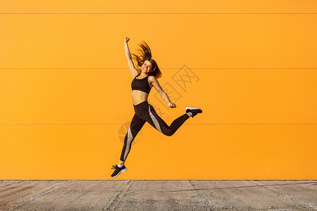 但使龙城飞将在年轻的黑发女人和运动锻炼 在户外运动员城市生活方式露齿训练橙色空气活动女士活力背景