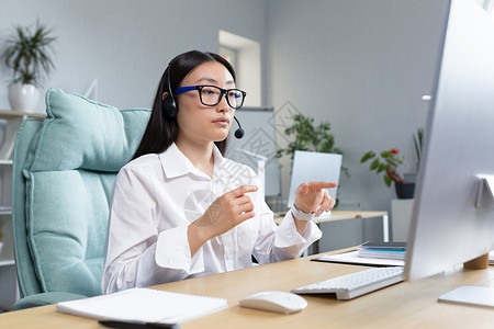 施工请注意安全远程工作的顾问女性使用耳机进行视频通话 与客户交谈 求助热线 在办公室工作的亚洲女性背景