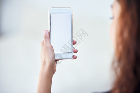 手拖手机阅读来自同龄人 仇恨者和操控者在互联网上的评论 对一名持有带空白屏幕的手机的不明女性的近距离拍摄背景