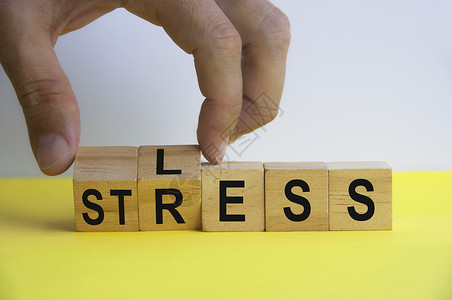 较少手持木制立方体 有LESS和STRESS的单词 复制空间背景