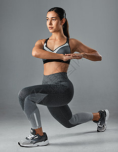 愿你你愿意为结果做出牺牲吗？运动型年轻女子在灰色背景下锻炼的摄影棚照片背景
