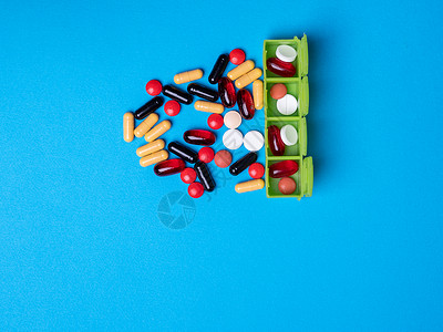 顶端有一个绿色组织者 里面有药丸 还有多色药丸和胶囊处方疾病治疗蓝色医疗框架宏观药物帮助药剂背景图片
