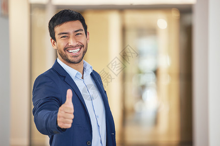 一位年轻商务人士在办公室露出大拇指的肖像 我还想看你的成功图片