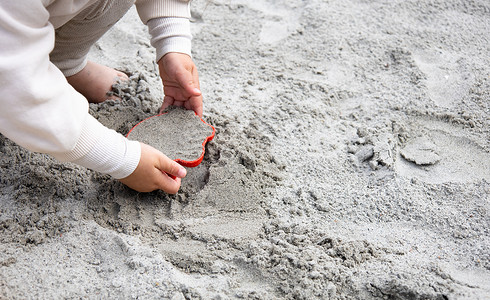 女孩抹粉饼一个小女孩在沙子里玩耍 在游乐场的沙箱里喜悦沙坑幼儿园公园女儿乐趣活动盒子童年玩具背景
