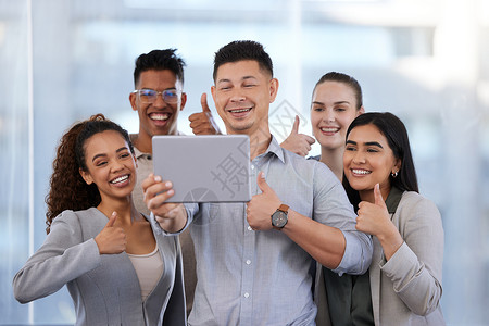 比试五好多少比试五好 拍摄一群年轻商务人士 拿着数字平板电脑拍自拍 在现代办公室露出拇指的镜头背景