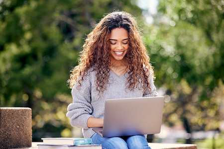 利用笔记本电脑在校园外学习的有吸引力的年轻女学生 她正在校外研读课程背景