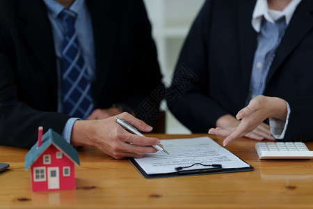 不粘纸特写商务人士指向和签署购买房子的协议 银行经理和房地产概念背景