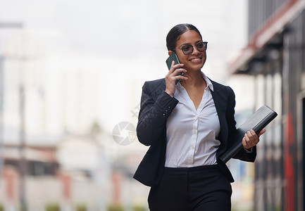 明朝那些事早上第一件事就是完成那些重要的电话 一位迷人的年轻女商务人士在早上通勤时穿过城市并使用她的手机背景