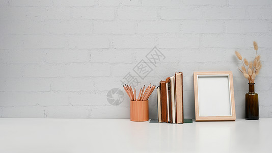 白色桌子上有空白图片框 书籍和铅笔架的家庭办公桌 复制广告文本的空间背景图片