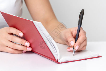 美甲笔手在笔记本上写笔记日记美甲办公室学生教育皮肤日程指甲学习工作背景