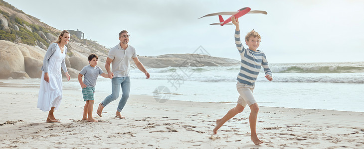 飞机小爱素材快乐的白人父母和孩子们一起玩玩具飞机 同时在海滩上度过一个轻松愉快的家庭暑假 享受美好时光 慈爱的爸爸妈妈与开朗的儿子们融为一体背景