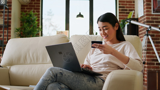快乐的年轻成年女性在购物网站上插入信用卡证书 以在线支付; 在网上付款背景图片