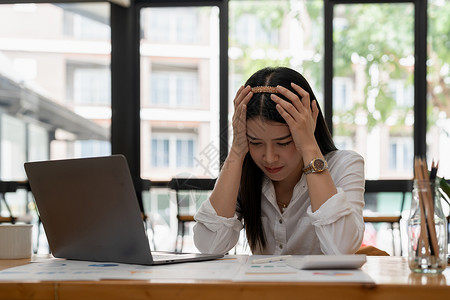 金融纾困年轻迷人的亚洲女商务人士在办公桌前睡觉 打瞌睡或小睡 疲惫的女商务人士在办公室拿着账单和文件夹 疲惫的年轻女商务人士带着笔记本电背景