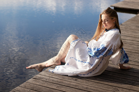 湖岸码头上身着绣有乌克兰民族服装的女孩 乌克兰独立日 宪法 vyshyvanka 日 户外穿蓝色裙子的年轻女子连衣裙装饰品女性旅背景图片