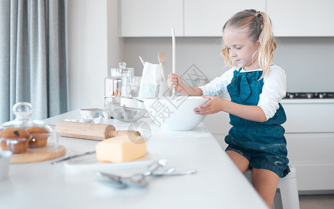 搅拌一碗面糊的小女孩 幼儿独自在厨房里烘烤 小女孩坐在她的厨房柜台前 拿着搅拌碗的白人女孩 在家烘烤的幼儿背景图片