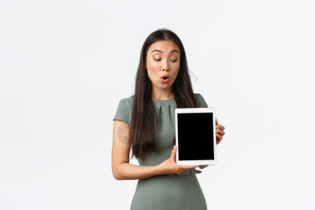 商品热销表情小企业主 从家庭概念开始和工作 穿着裙子的亚洲女性惊讶而深刻地看着数字平板电脑屏幕 表情震惊 检查库存中的新商品背景