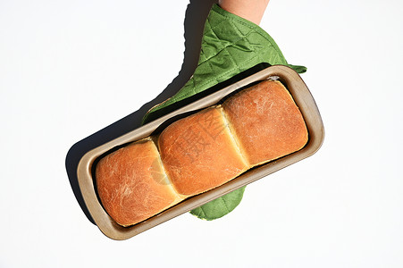 厨师手的顶端视镜 在厨房手套里 拿着新鲜烤热全熟的面包 白底孤立于世背景图片