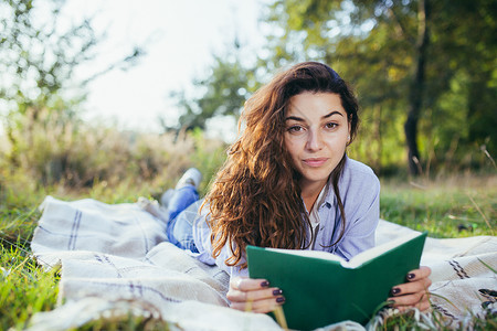 美丽的年轻女学生会读书 读书 躺在自然中的草地上休息摄影大学学生乐趣人体青年眼镜享受人脸背景图片
