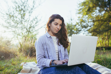 美丽的年轻女学生远程学习 在笔记本电脑上上网写 写 读书农田活动部位计算机服装互联网庭院商业成人手机背景图片