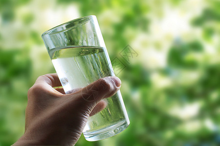 手握着一杯水 在自然绿色背景的户外特写上饮食生活方式矿物质浅色口渴液体生态饱和气泡身体背景图片