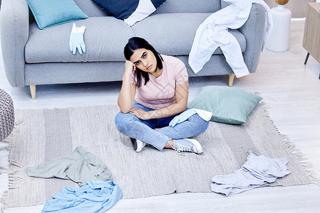乱糟糟的环境造成了混乱的心态 一个年轻女子在家里打扫休息室背景图片