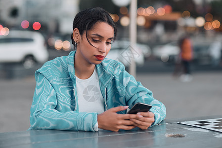 坐在户外咖啡馆时 有心理健康问题的悲伤 沮丧和压力大的女性在手机上发短信 年轻女性在聊天或浏览社交媒体时收到负面回应或坏消息背景图片