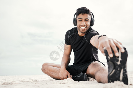 兔年好一点右侧的播放列表会让你心情好一点 一个年轻人在沙滩上伸展时 戴着耳机穿戴耳机背景