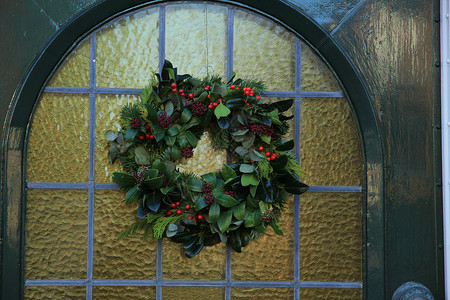 槲寄生花圈古老的圣诞节花环 门上有装饰玻璃门廊庆典假期前门花圈入口丝带房子蓝色背景