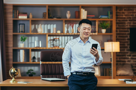 施工请注意安全现代家庭办公室成功的亚洲商务人士 看看电话屏幕 请看电话屏幕男人标志技术成人施工用户商业商务人士电脑背景