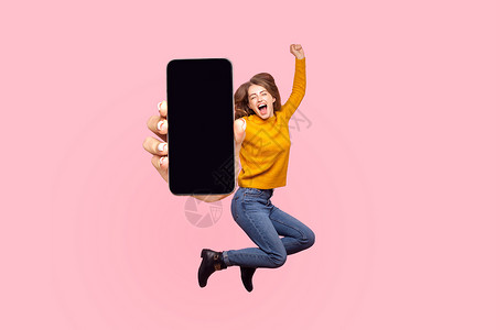 空的应用程序快乐的年轻女士在空中飞行和跳跃 显示巨大的移动空屏幕展示女孩飞跃手机空气粉红色享受广告喜悦蹦床背景