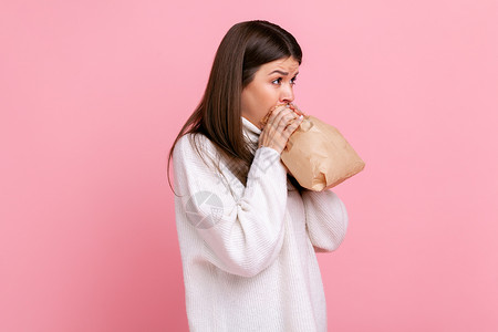 安家神经紧张的女孩的侧面观点 呼吸在纸袋里 改善健康状况 克服压力背景