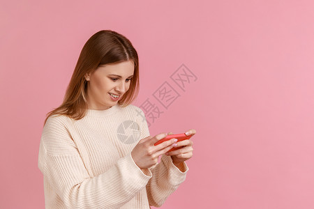 快乐的金发美女拿着智能手机 玩电子游戏 成功完成成绩赛程 幸福的金发女郎背景