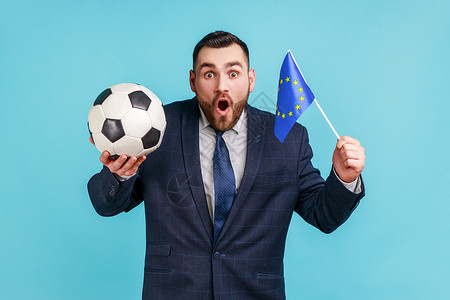 佩戴黑西装的人非常惊讶 举着欧洲联盟和足球的旗子 支持最喜爱的冠军赛球队 (注背景图片