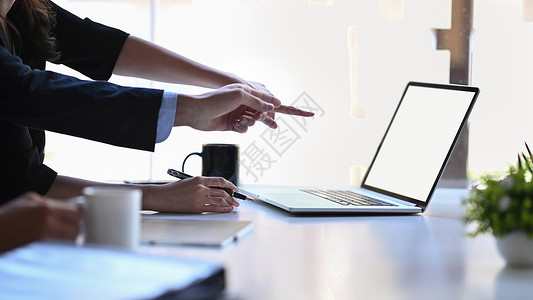 商务人统计数据被裁剪的两名商务人士在笔记本电脑屏幕上指着背景