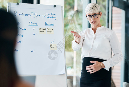 为她的团队提供一些进一步的培训 在办公室做演示时使用白板的怀孕女商务人士背景图片
