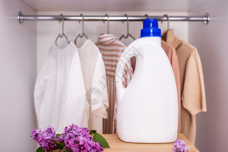 更衣室标识白色洗涤剂瓶装模型 放在衣橱和衣服的背景上标签女佣夹克清洁工洗涤衣架纺织品样本家庭洗澡背景