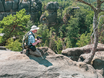 鲍尔帽子有摄影机的观光客 正在施拉姆斯泰因岩石后面拍照相机高地摄影师三脚架老人假期游客全景景点侵蚀背景
