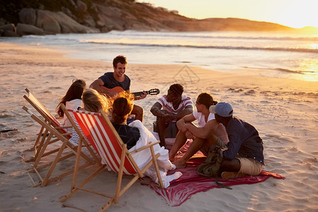 真正的放松好朋友会留下美好的回忆 一个男人和他的朋友坐在沙滩上弹吉他背景