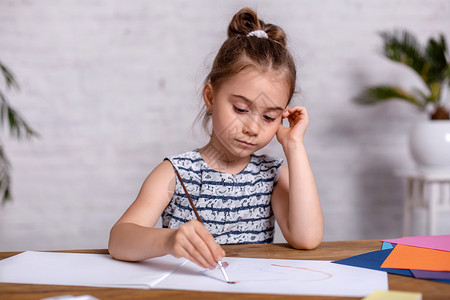 鼓动坐在桌上的小女孩 用油漆画画画草图女孩童年享受桌子绘画沉思快乐教育笔记本背景