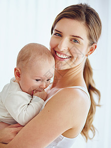 母亲与男婴结合 微笑着在家里的房间里享受家庭时光 一个快乐 充满爱心和关怀的单亲父母抱着或抱着一个可爱 可爱的小新生儿的肖像背景图片