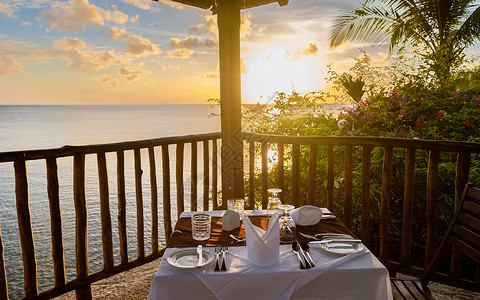 海洋食物日落时吃晚饭桌 在海洋间浪漫晚餐 观看美丽的加勒比海大海果汁成人快乐用餐热带庆典海滩女性家庭蜡烛背景