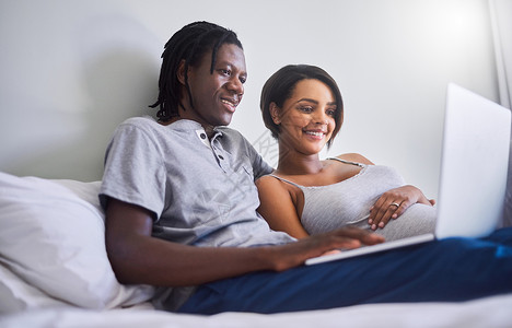 让我们来看看这周的怀孕情况 一对期待中的夫妇在家里浏览互联网背景图片