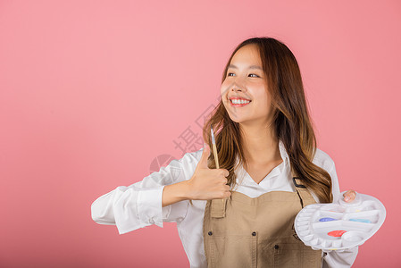 持有刷子和油漆调色盘的亚洲年轻女艺术家图片