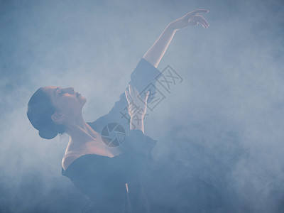 熟练度年轻美丽的芭蕾舞演员在烟雾舞台上跳着现代芭蕾舞 用手进行流畅的动作 现场身着黑衣的女子背景